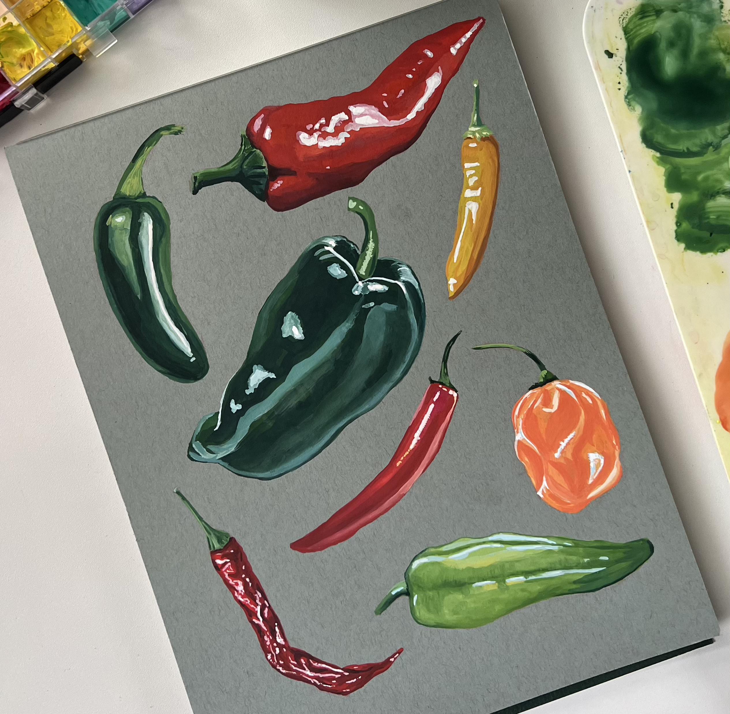 Colorful painted chili peppers on gray background, showcasing various types and styles.