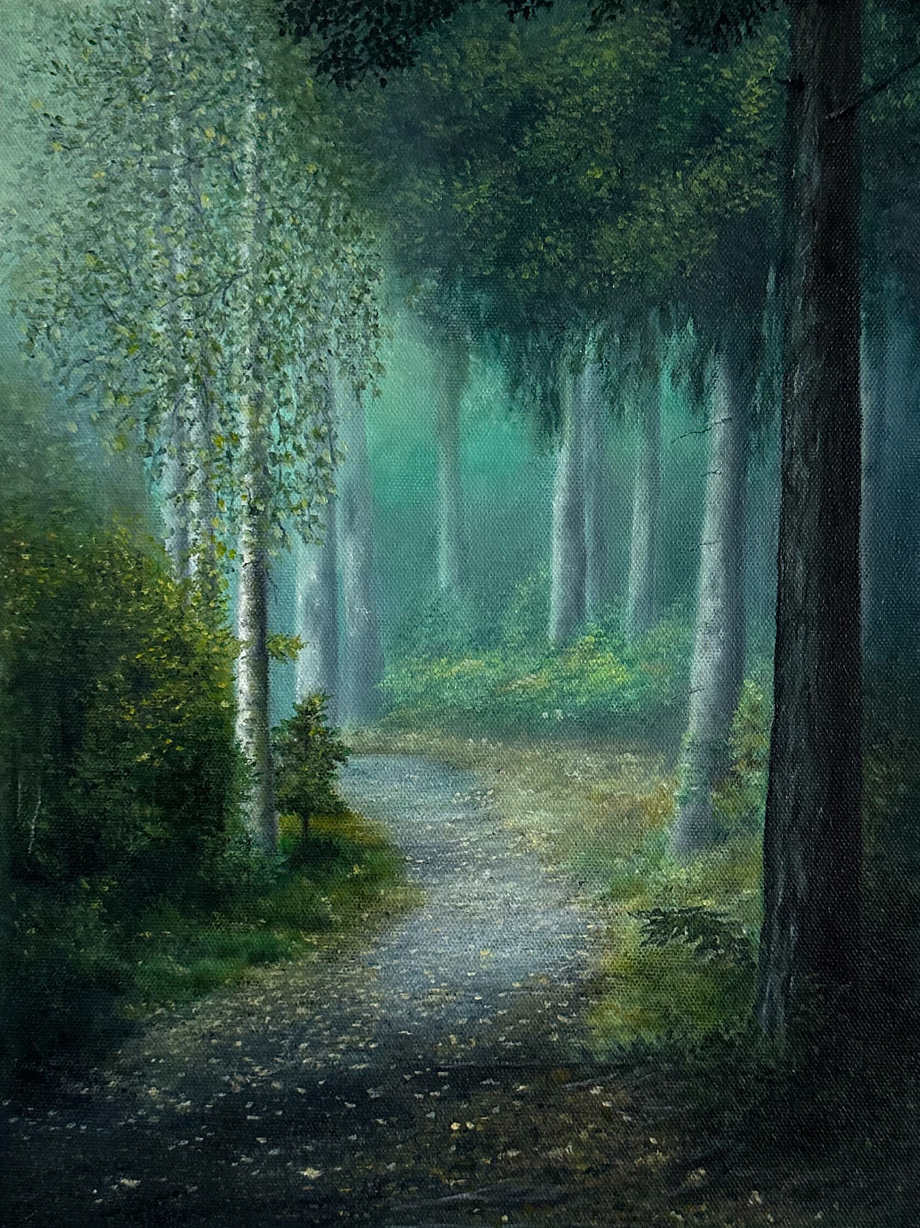 Serene forest path surrounded by lush green trees and mist.