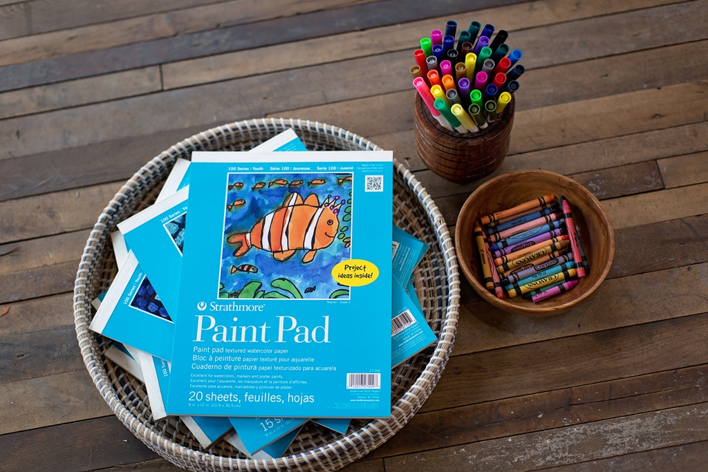 "Strathmore paint pads and colorful markers on a wooden surface."